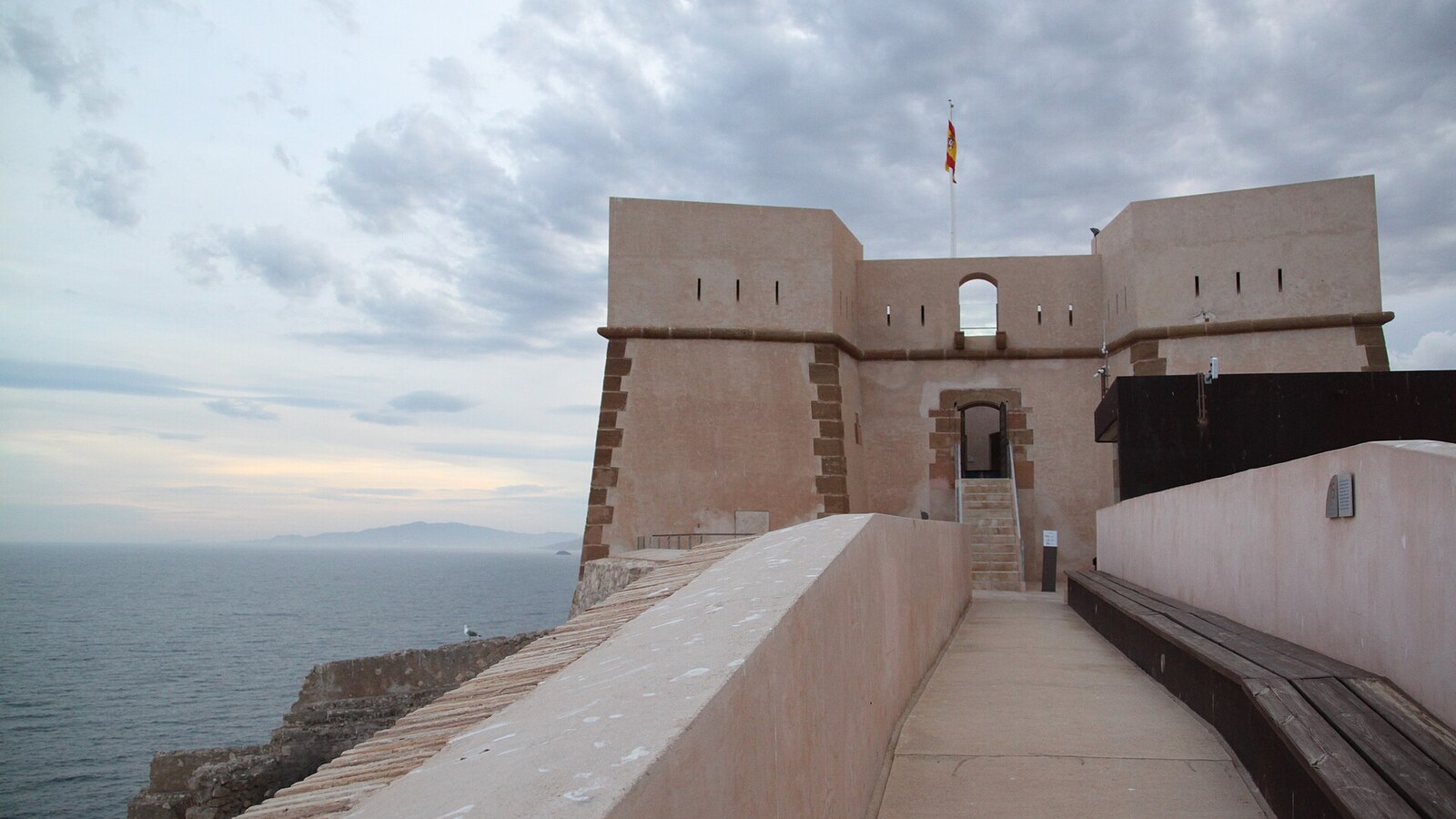Burg San Juan de las Águilas über dem Meer, Zugang über einen gemauerten Weg. Wetter an der Costa Blanca und der Costa Cálida am 17.10.2026: einzelne Schauer, 23 bis 24 Grad.