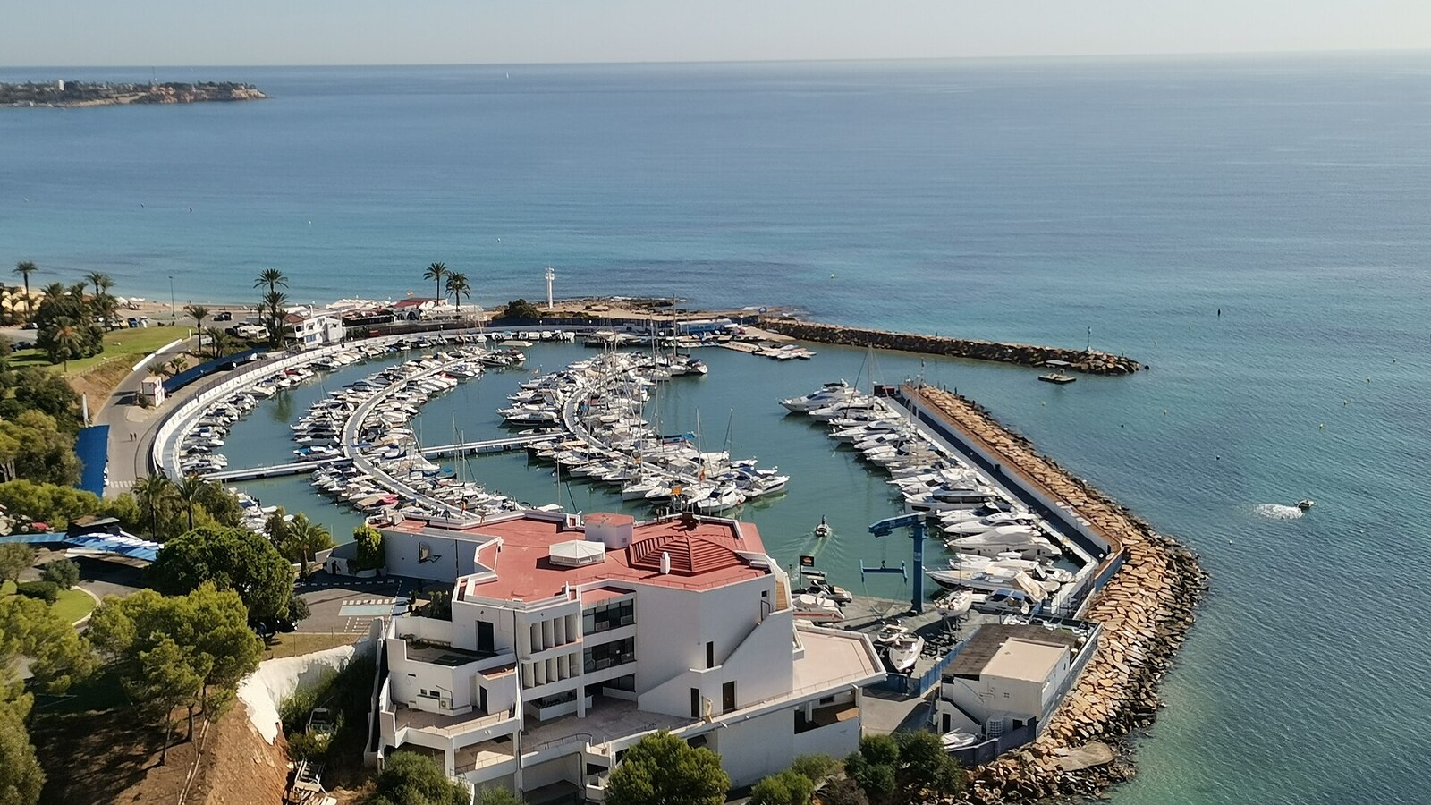Sporthafen und Gebäude des Club Náutico von Dehesa de Campoamor von oben, Meer bis zum Horizont.