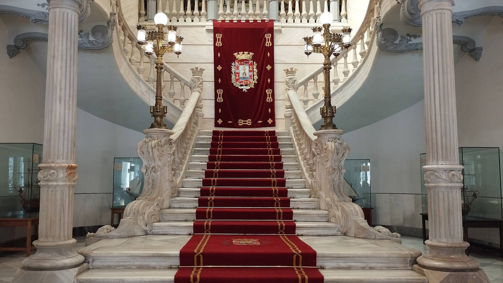 Marmortreppe mit rotem Teppich und Stadtwappen im Palacio Consistorial von Cartagena.