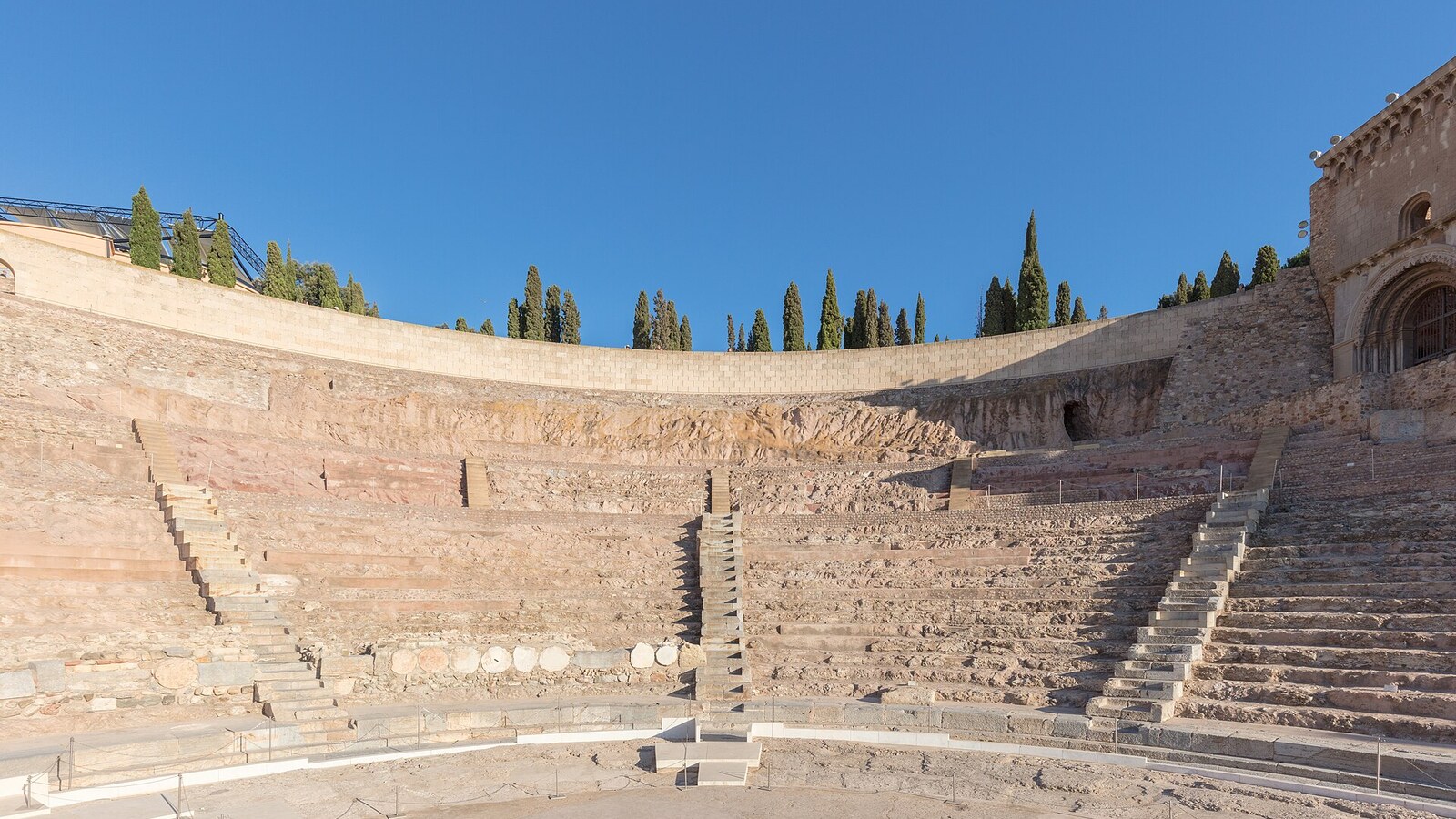 Sitzreihen des römischen Theaters von Cartagena, Zypressen am oberen Rand.