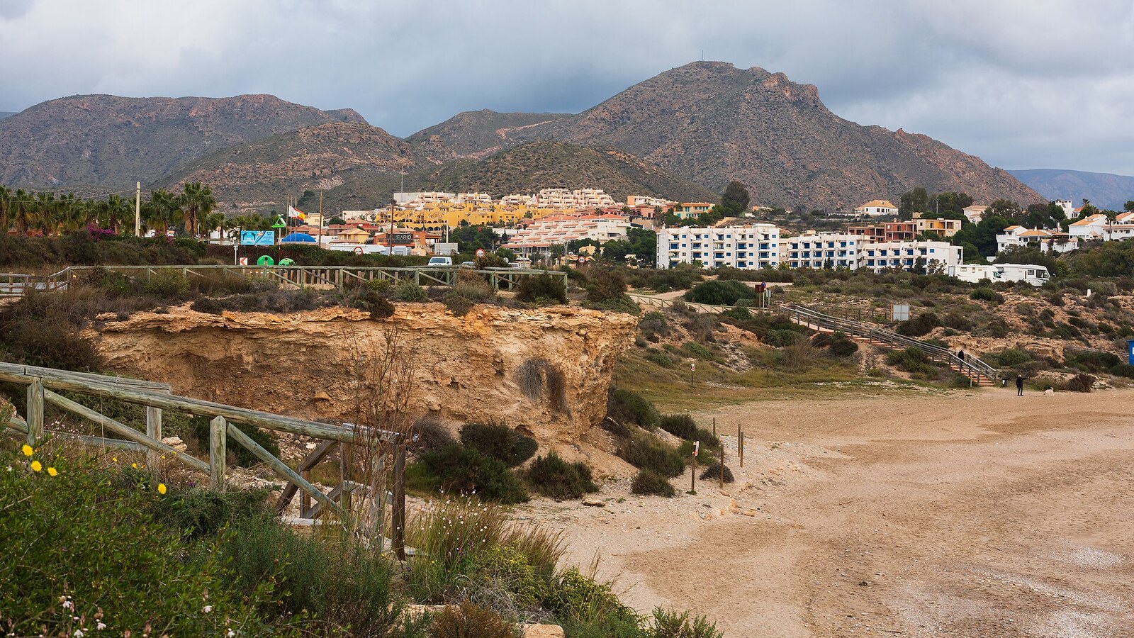 Strand Playa del Mojón in Puerto de Mazarrón, dunkle Wolken über sonnenbeschienenem Ufer. Wetter an der Costa Blanca am 03.10.2026: einzelne Schauer, 24 bis 28 Grad.