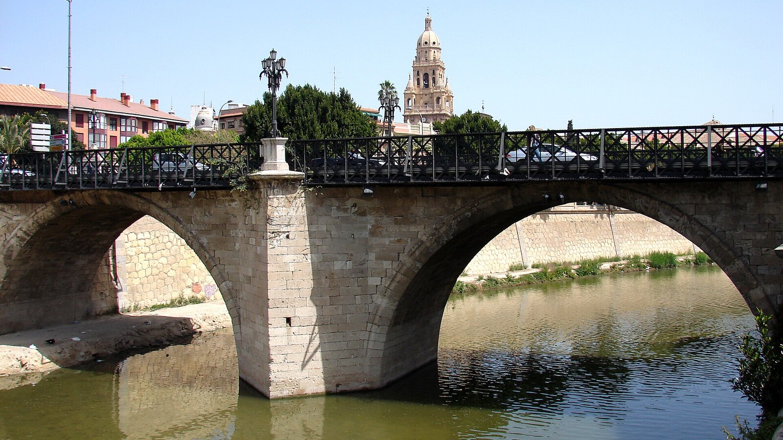 Die alte Steinbrücke Puente de los Peligros über den Río Segura in Murcia, der Turm der Kathedrale dahinter.