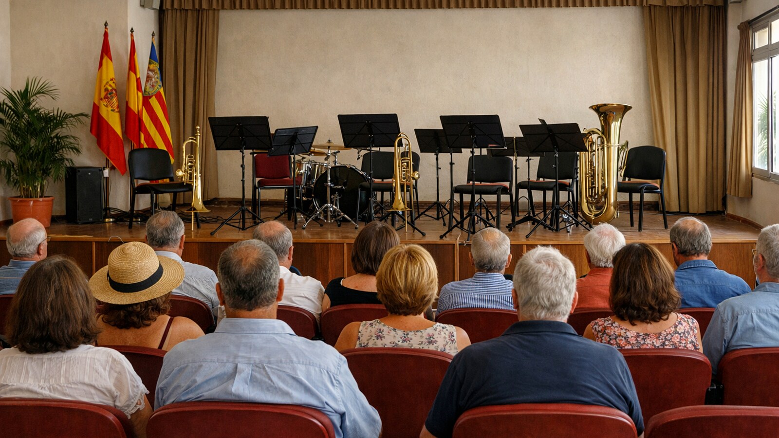 In einem schlichten Konzertsaal sitzt Publikum vor einer kleinen Bühne mit Notenständern, Blechblasinstrumenten, Schlagzeug und spanischen sowie regionalen Fahnen, während keine Musiker zu sehen sind (KI-Symbolbild).