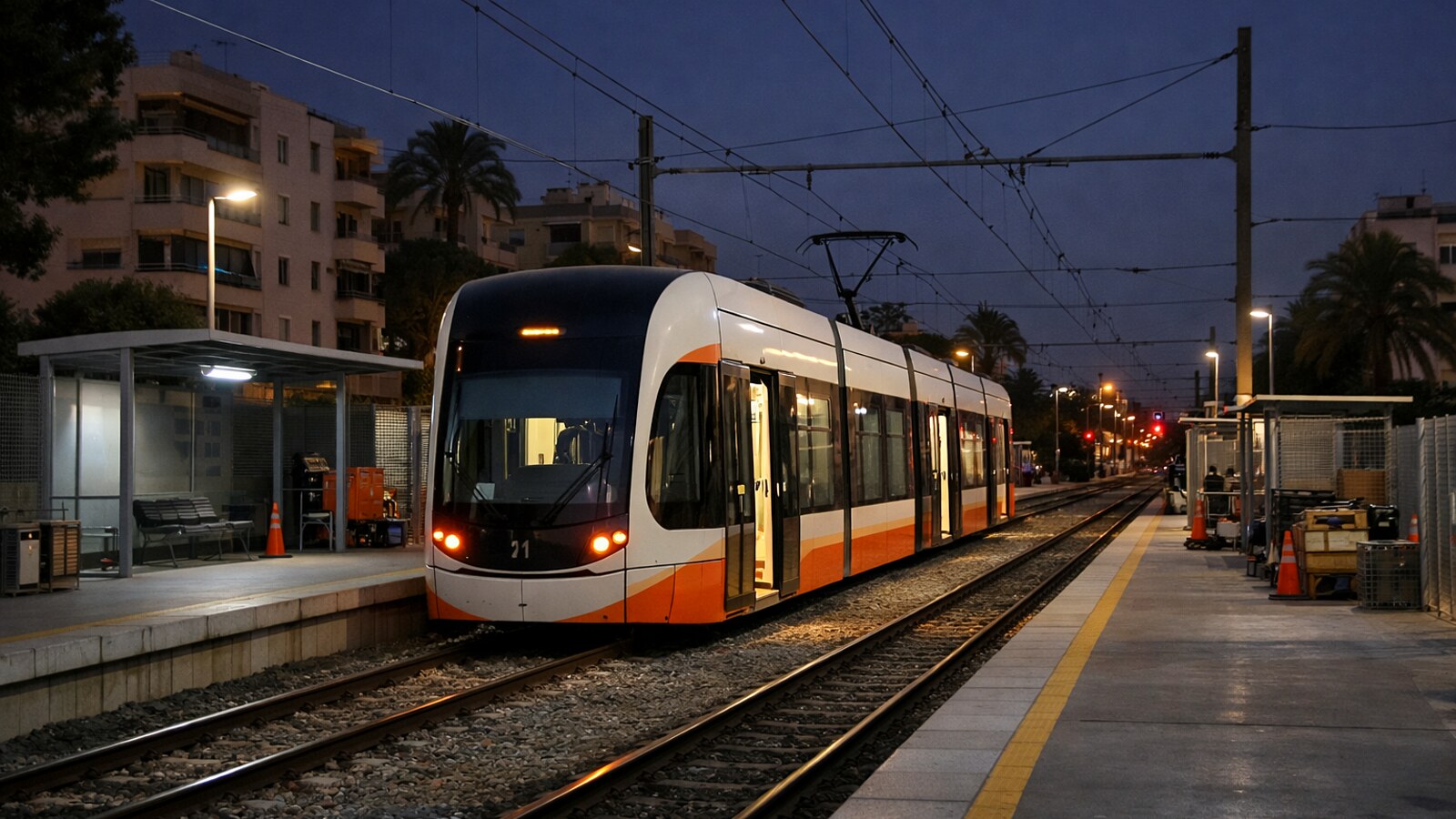 Eine moderne Straßenbahn steht nachts an einer beleuchteten Haltestelle mit leeren Bahnsteigen, Oberleitungen und wartungsähnlicher Umgebung in einem städtischen Wohngebiet (KI-Symbolbild).