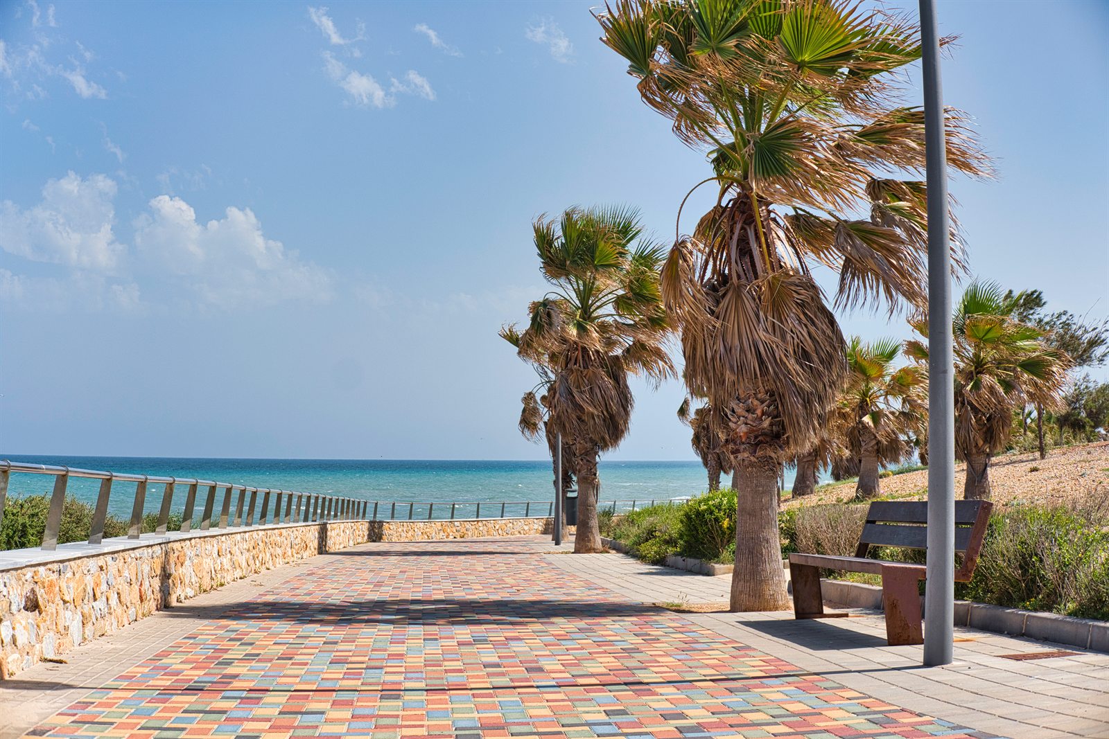 Promenade mit buntem Pflaster und Palmen, Quellwolken über dem Meer. Wetter an der Costa Blanca und der Costa Cálida am 15.10.2026: bedeckt, 23 bis 27 Grad.