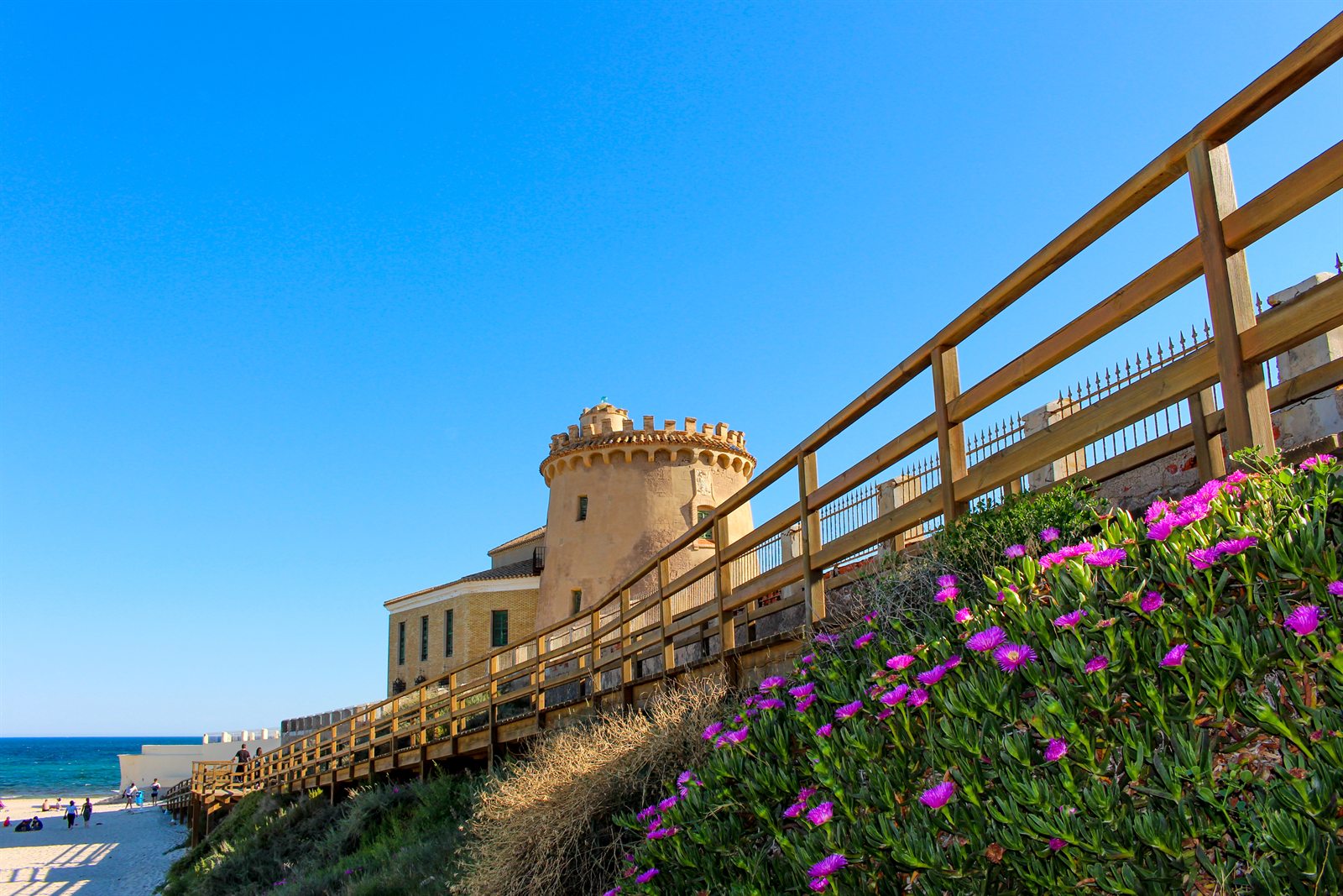 Wachturm von Torre de la Horadada über dem Strand, blühender Hang, wolkenloser Himmel. Wetter an der Costa Blanca und der Costa Cálida am 21.10.2026: heiter, 24 bis 27 Grad.